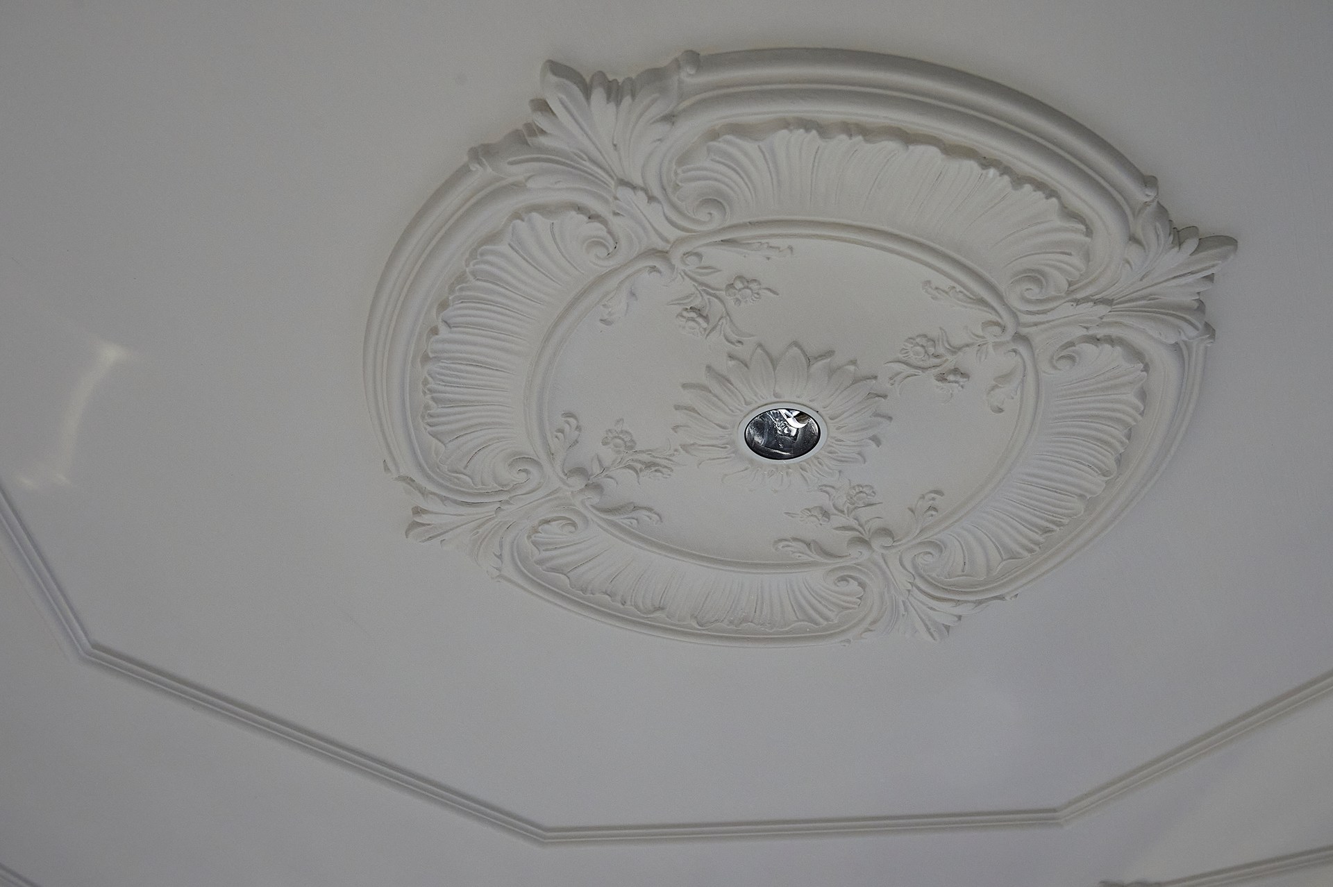Ozdobna rozeta sufitowa z rzeźbionymi detalami, podkreślająca architektoniczną dekorację sufitu.